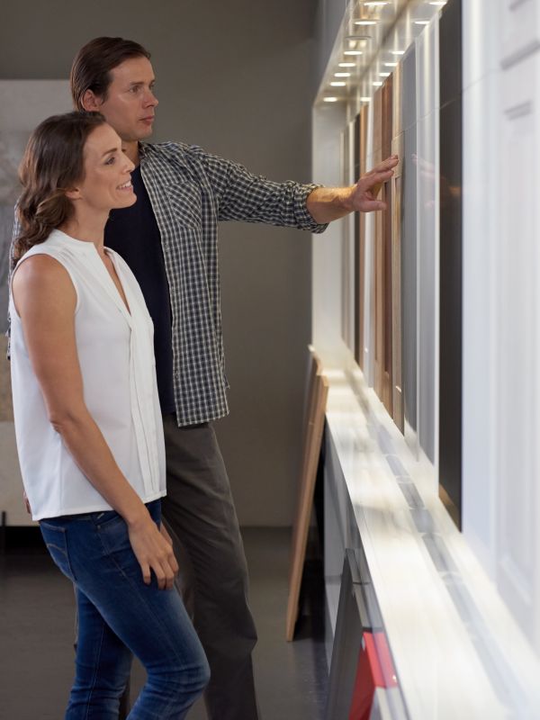 Couple looking at different materials and samples in modern kitchen shop showroom while designing their dream kitchen in their california MD home.