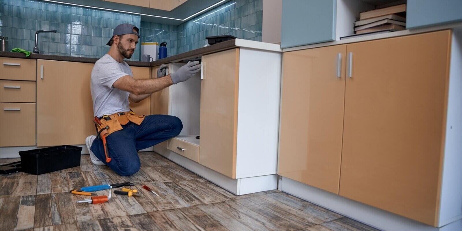 young caucasian worker measuring drawer in kitchen furniture