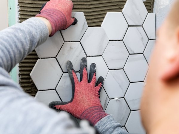 tiling - man laying marble texture hexagon tiles on the wall