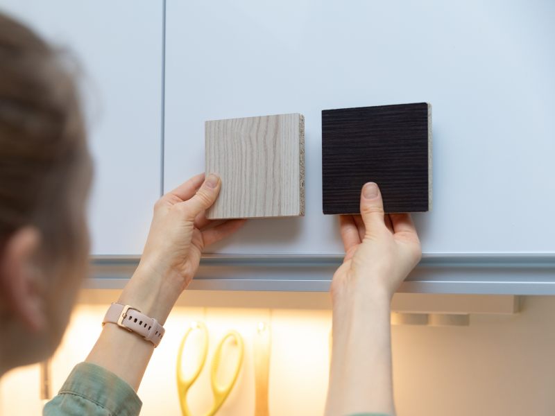 woman choosing kitchen cabinet materials from laminate samples