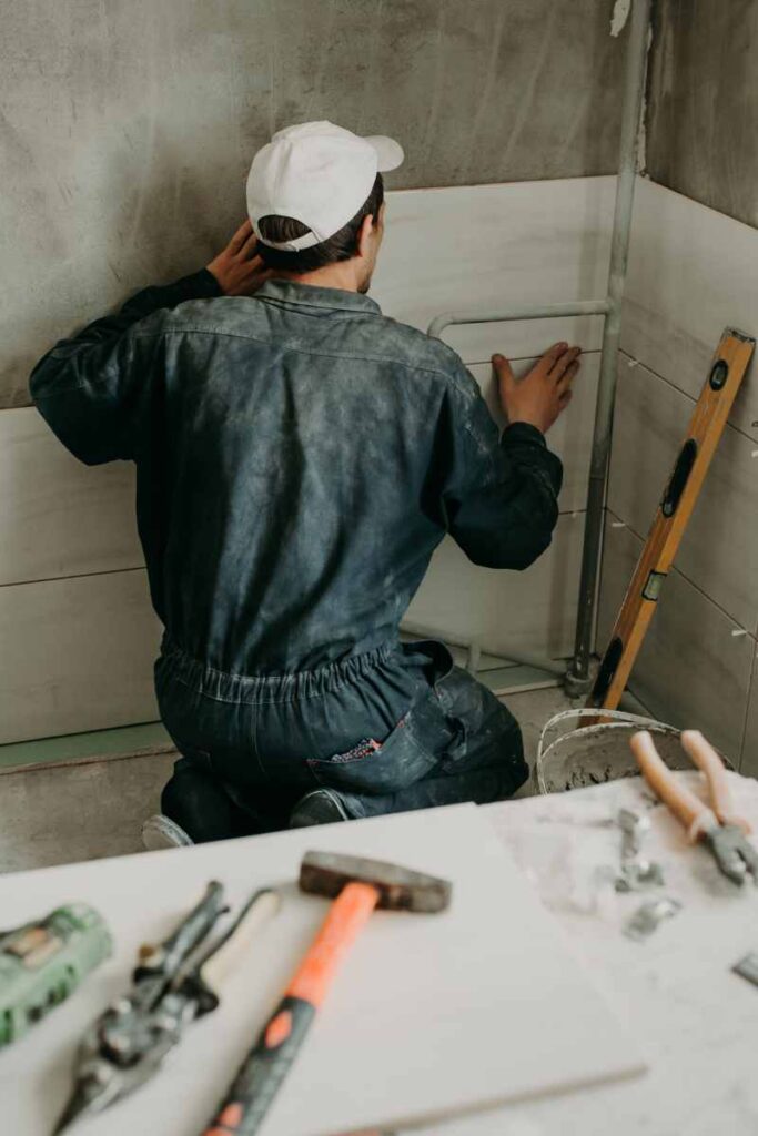 Worker repairman puts large ceramic tiles on the walls in the room