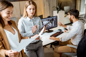 Employees Working on An Architectural Project with Blueprints and Computer
