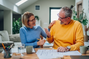 Senior Couple Sitting at Table and Looking into Blueprints of Their Aging-in-Place Remodel Layout