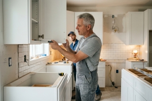 Contractor Installing White Wooden Kitchen Cabinets in Older Home