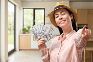 Smiling Young Woman Showing Dollars Saved After Financing Kitchen